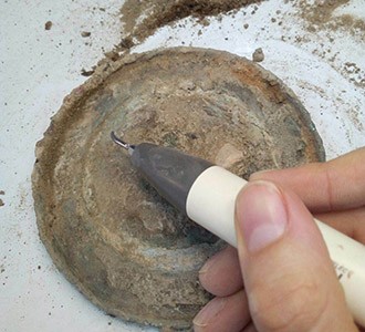 Proceso de limpieza de un disco de metal de origen griego